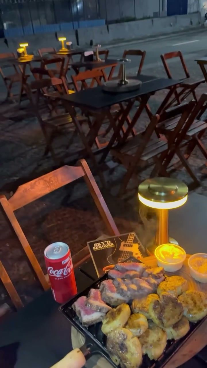 Mesas na calçada iluminadas à noite, com a tábua servida